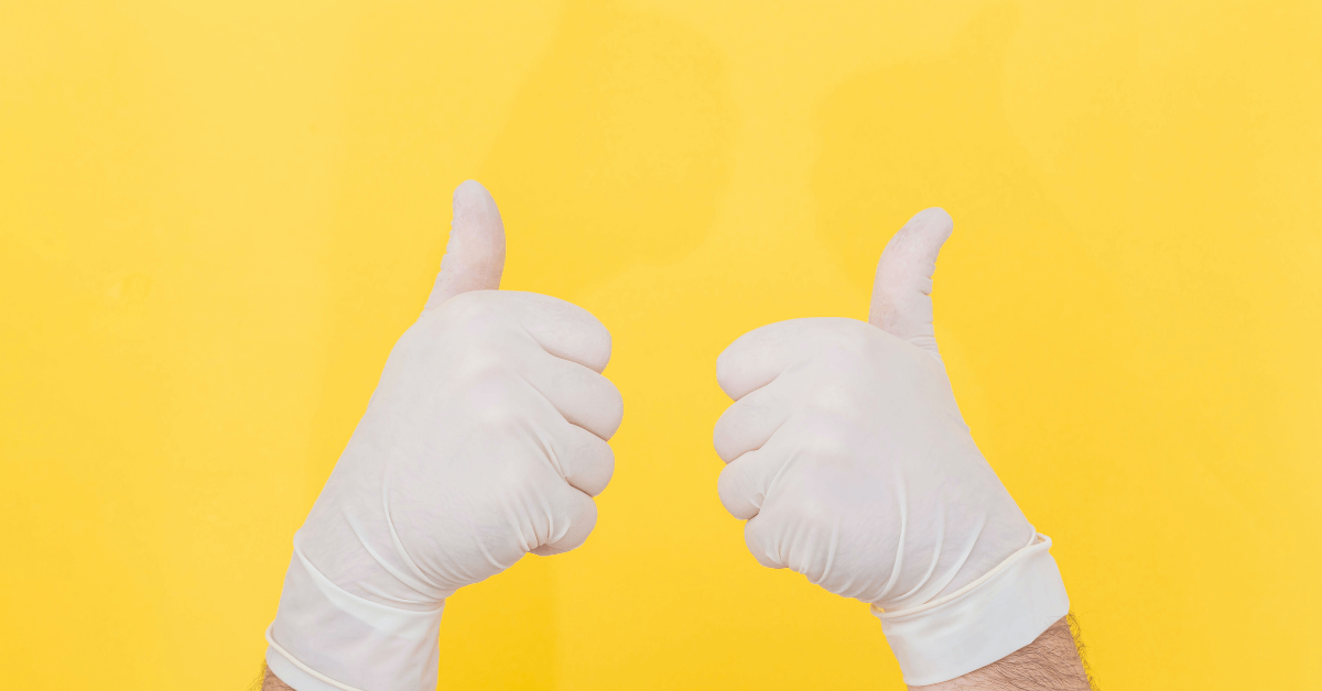 Two gloved hands giving a double thumbs-up on a yellow background