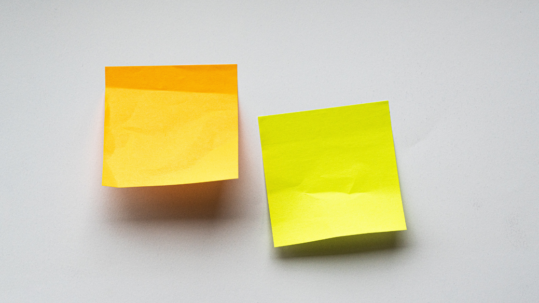 Two sticky notes stuck to a grey wall