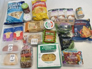 A counter filled with grocery items such as rice, meat, fish, veggies, cheese, and bread